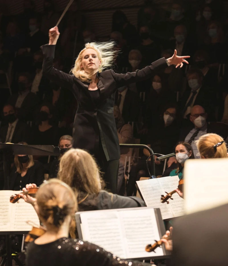 woman directing orchestra inside the concert hall