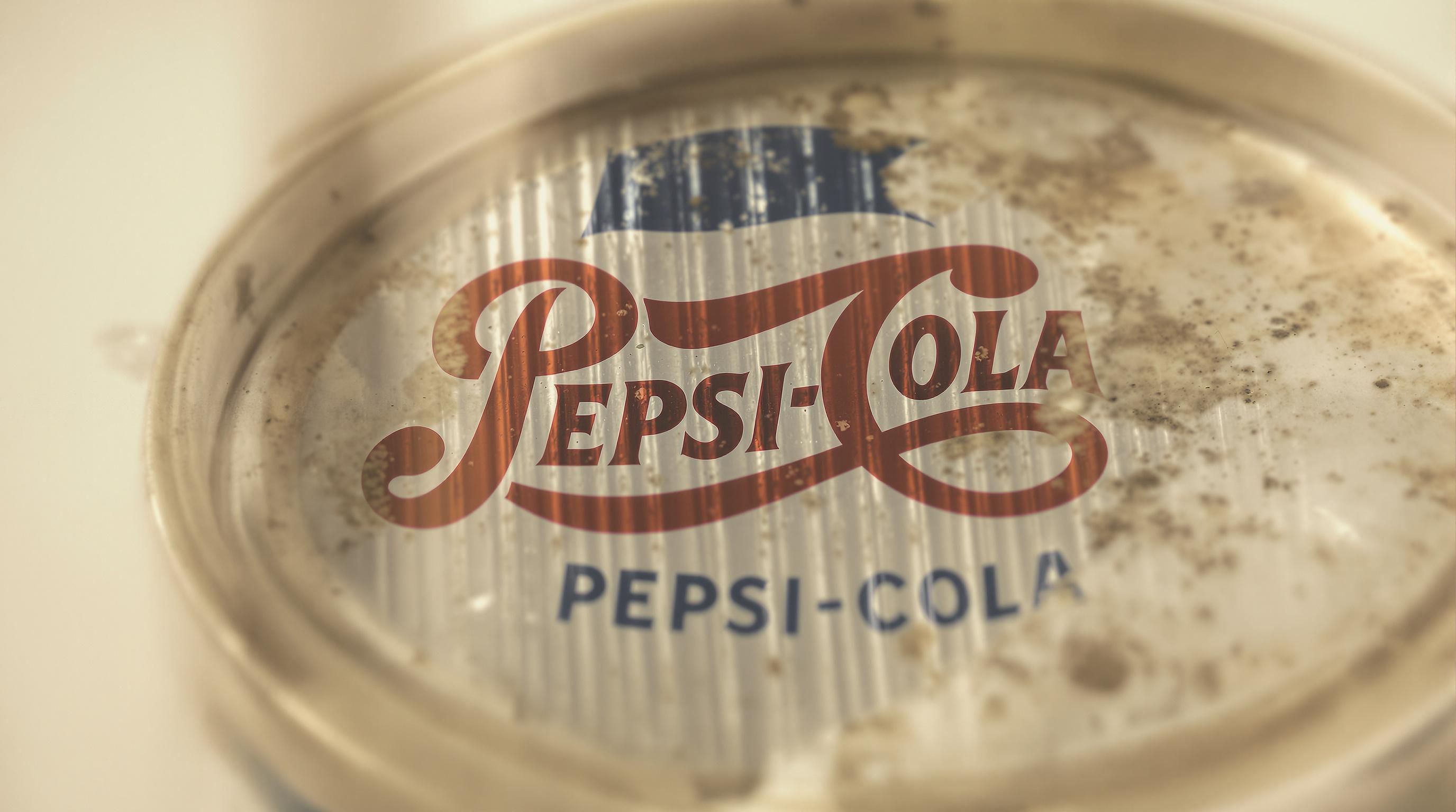 Display of various vintage Pepsi cans arranged chronologically showing the evolution of designs from 1970s through 1990s