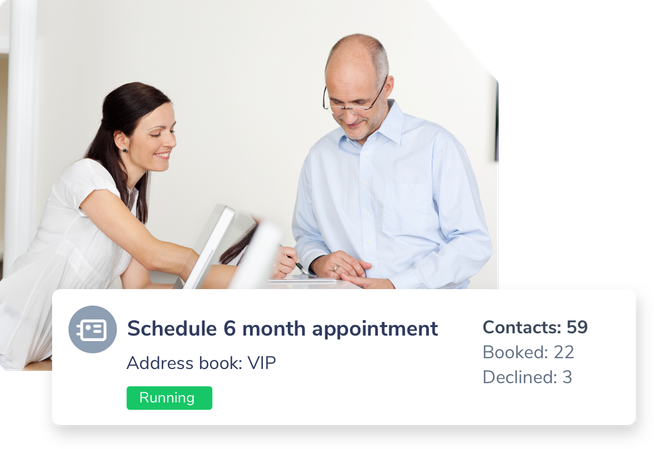 A receptionist and a dentist gather and stand together looking down at their appointment calendar with a sample of a scheduled reminder going out to a VIP list reminding patients to schedule their 6-month appointment.