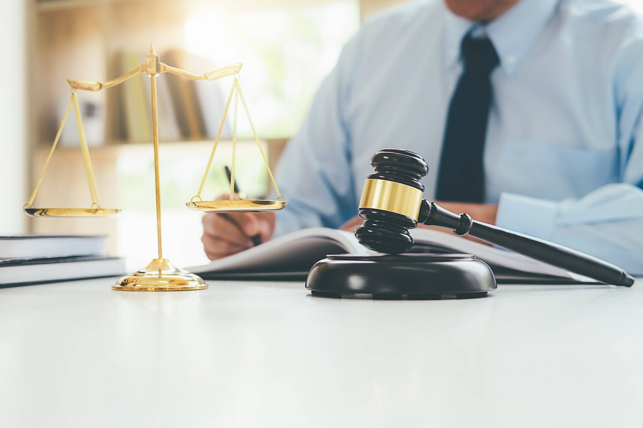 Lawyer or judge sitting in front of gavel and law scales of justice