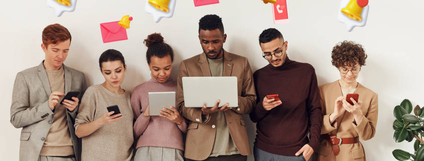 Multiple people standing together receiving message blast via their phones, tablets, or computers.