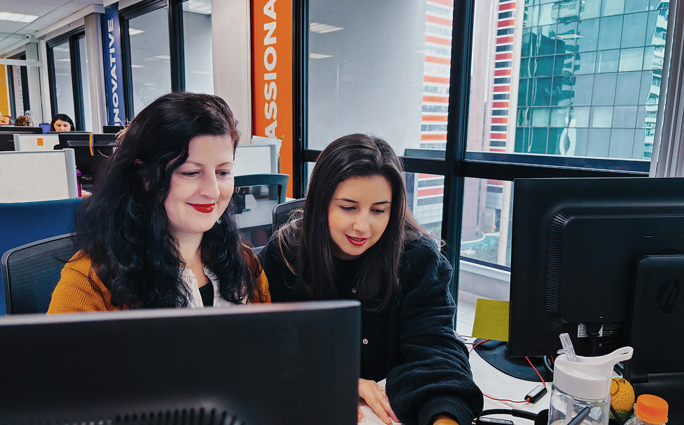 Two women sitting next to each other and looking at a monitor