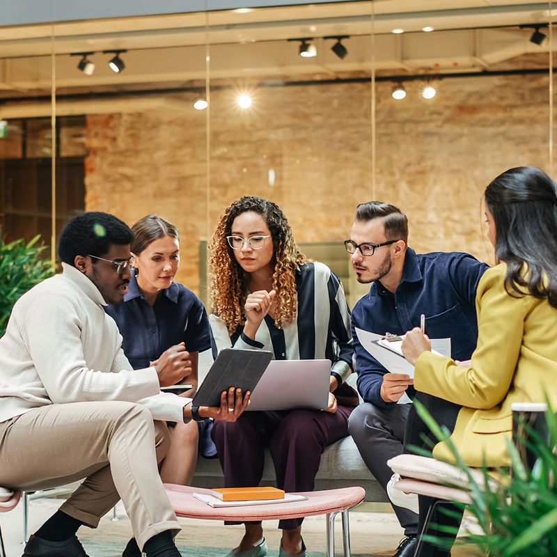 Four people sitting and looking at a laptop
