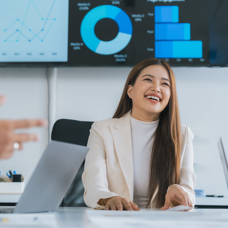 A woman sitting in front of a dashboard showing on the screen, laughing at someone off-camera