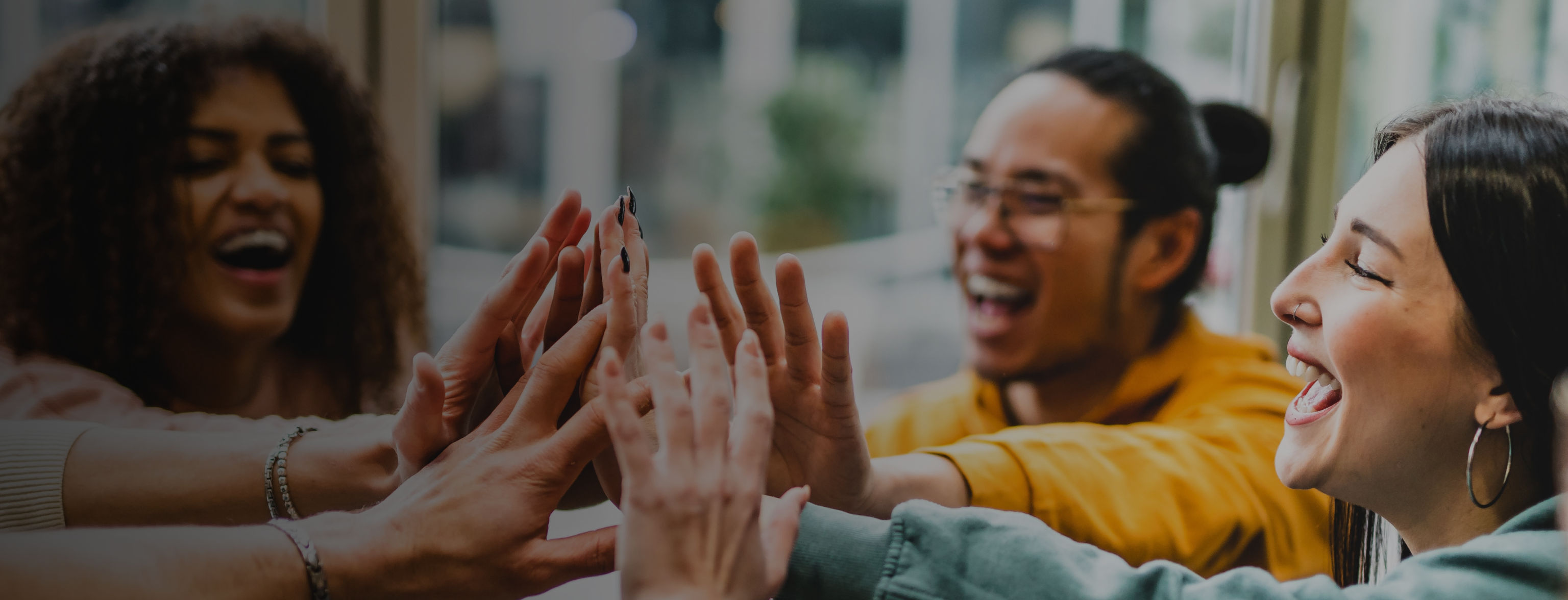 A selection of hands giving a joint high five, with a number of smiling people