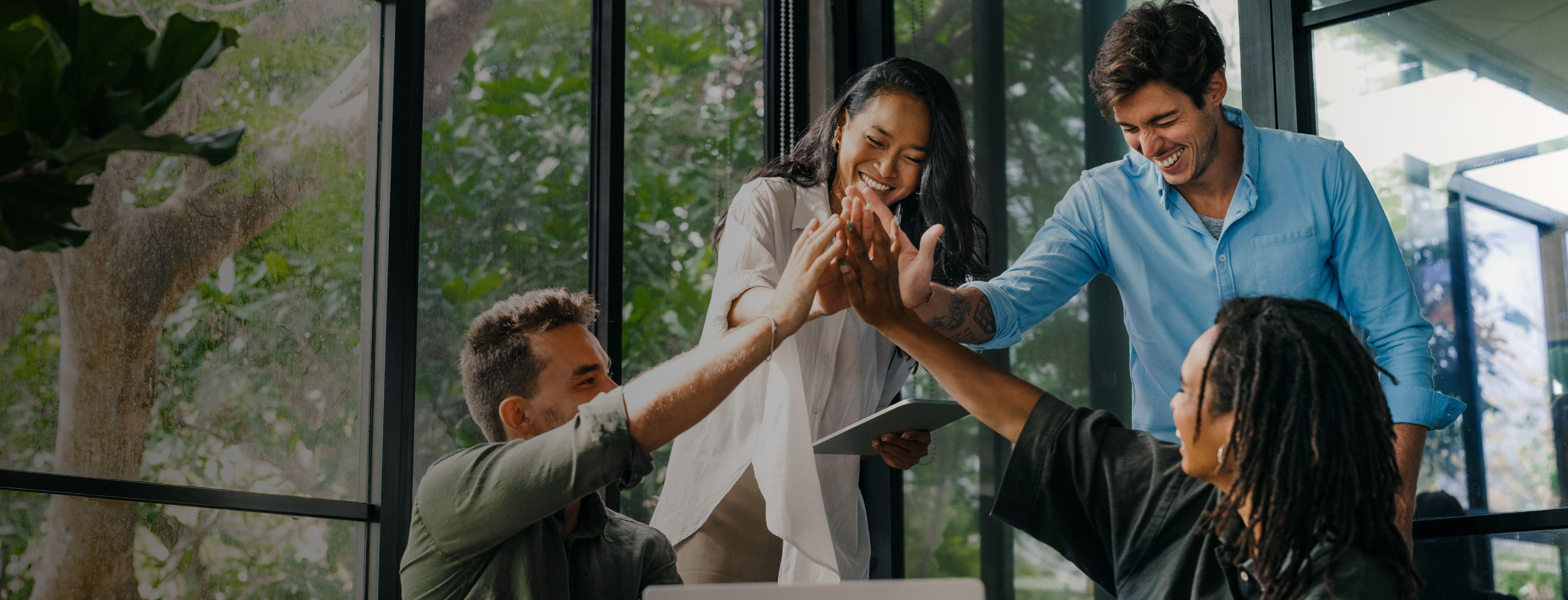Two people sitting and two standing all high fiving each other