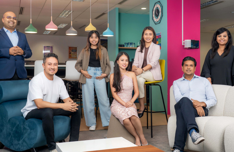 A group of people, some sitting, some standing, looking at the camera and smiling