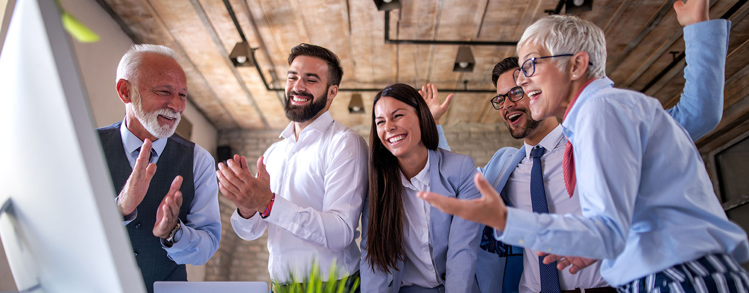 Five people standing and celebrating results on a computer screen