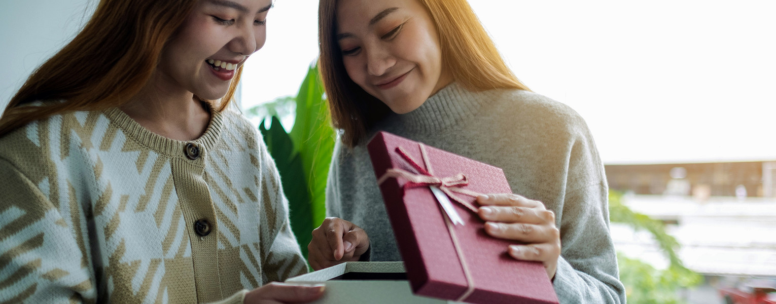 Two women opening a gift while smiling