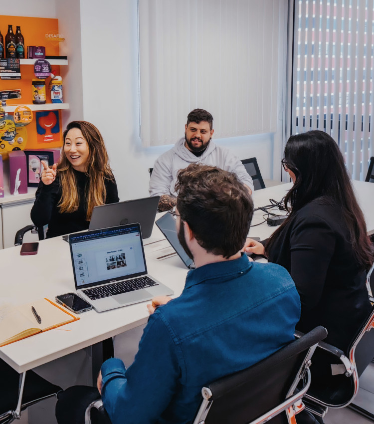Two people facing another two people, laptops between them, smiling at each other