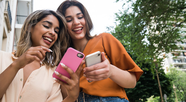 Two women looking at their phones and laughing