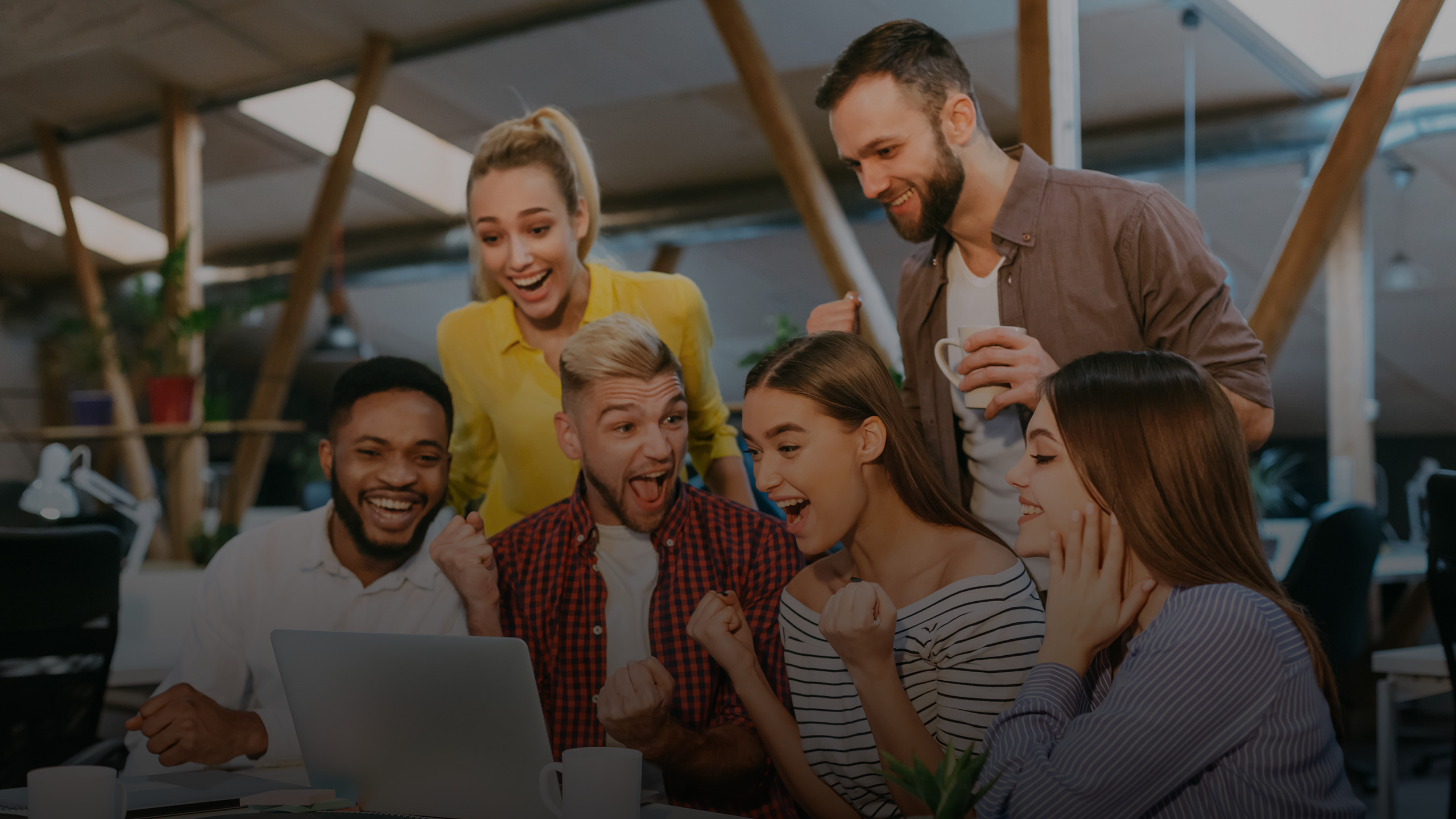 Six people celebrating in front of a laptop