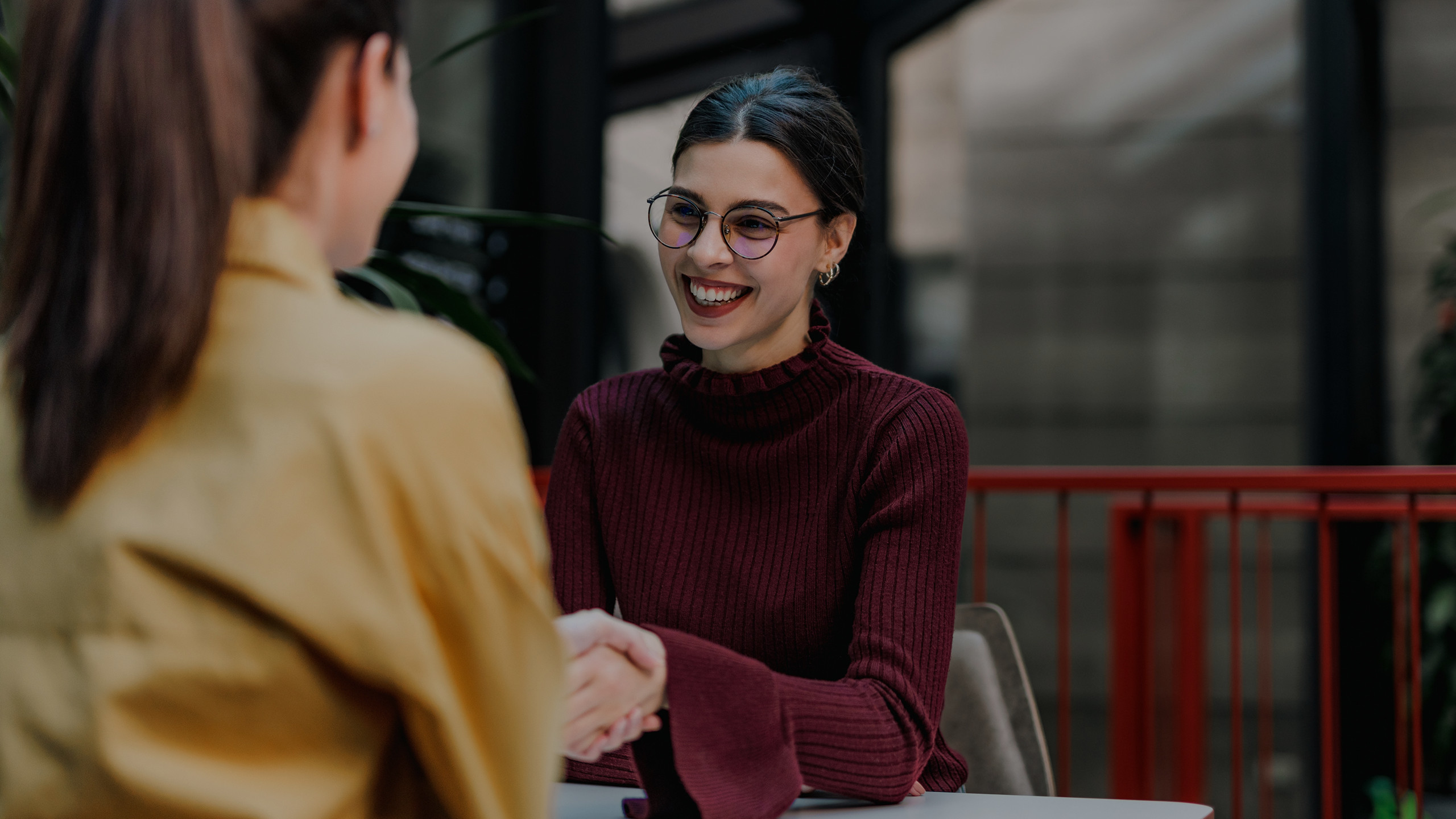 A smiling woman shaking hands with another woman