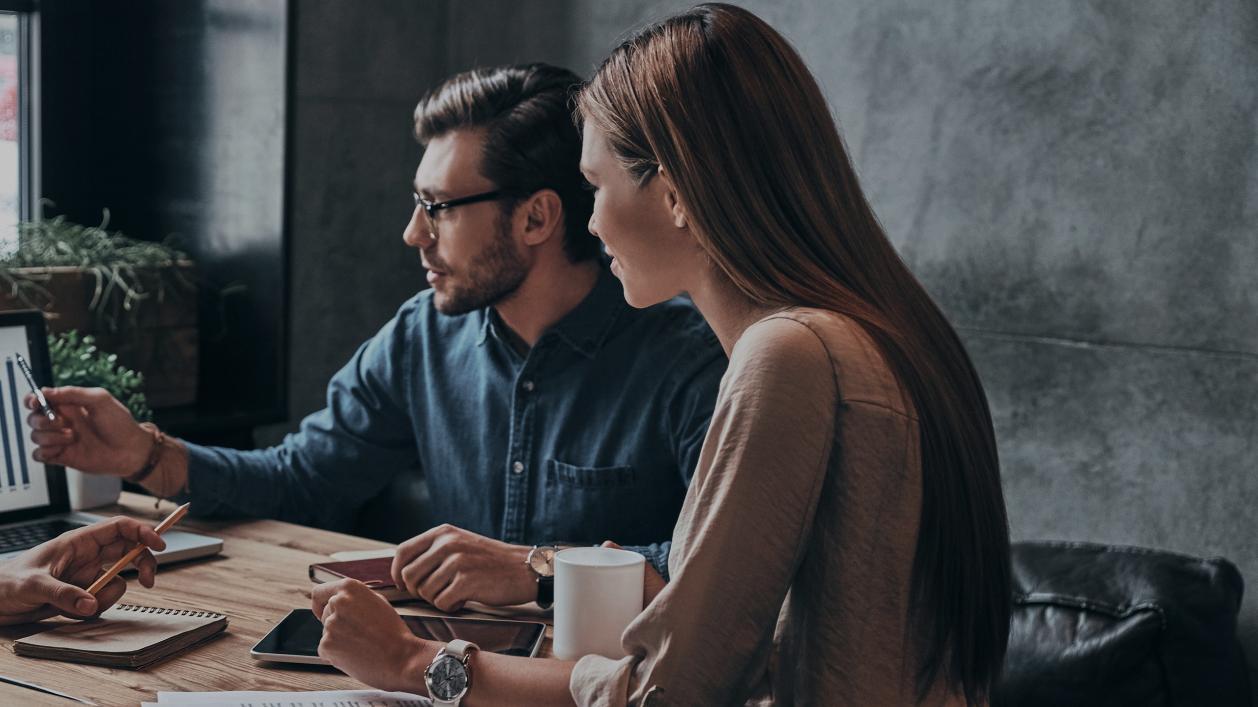 A man showing a woman the results from a chart on a laptop