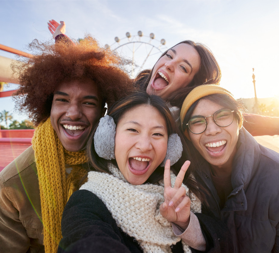 A group of four friends posing for a selfie, all smiling and showing excitement