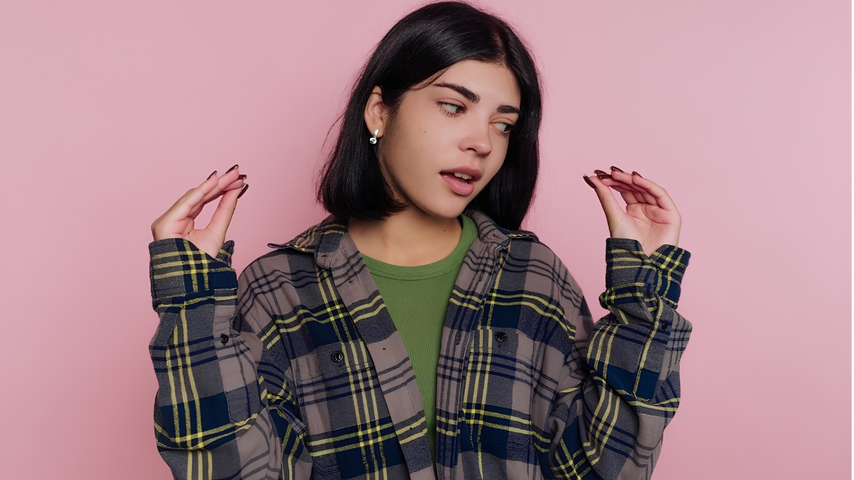 A woman gesturing with her hands in front of a pink background