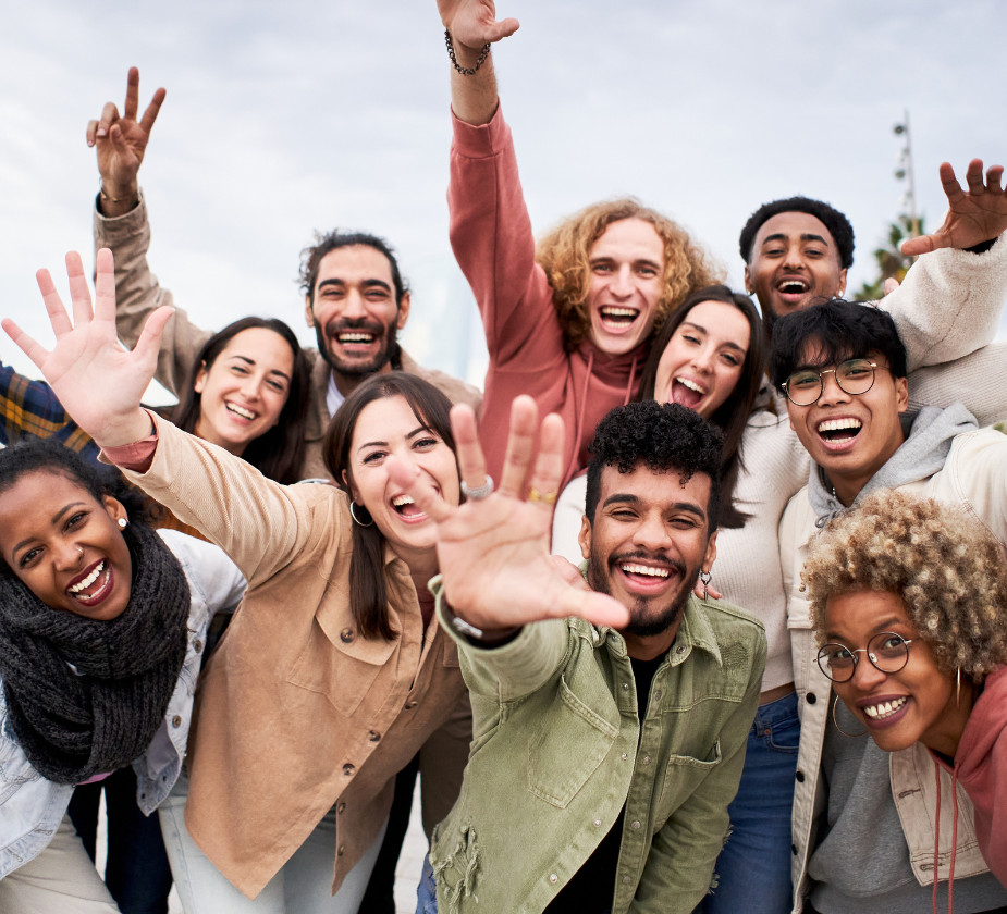 A diverse group of people smiling and waving at the camera