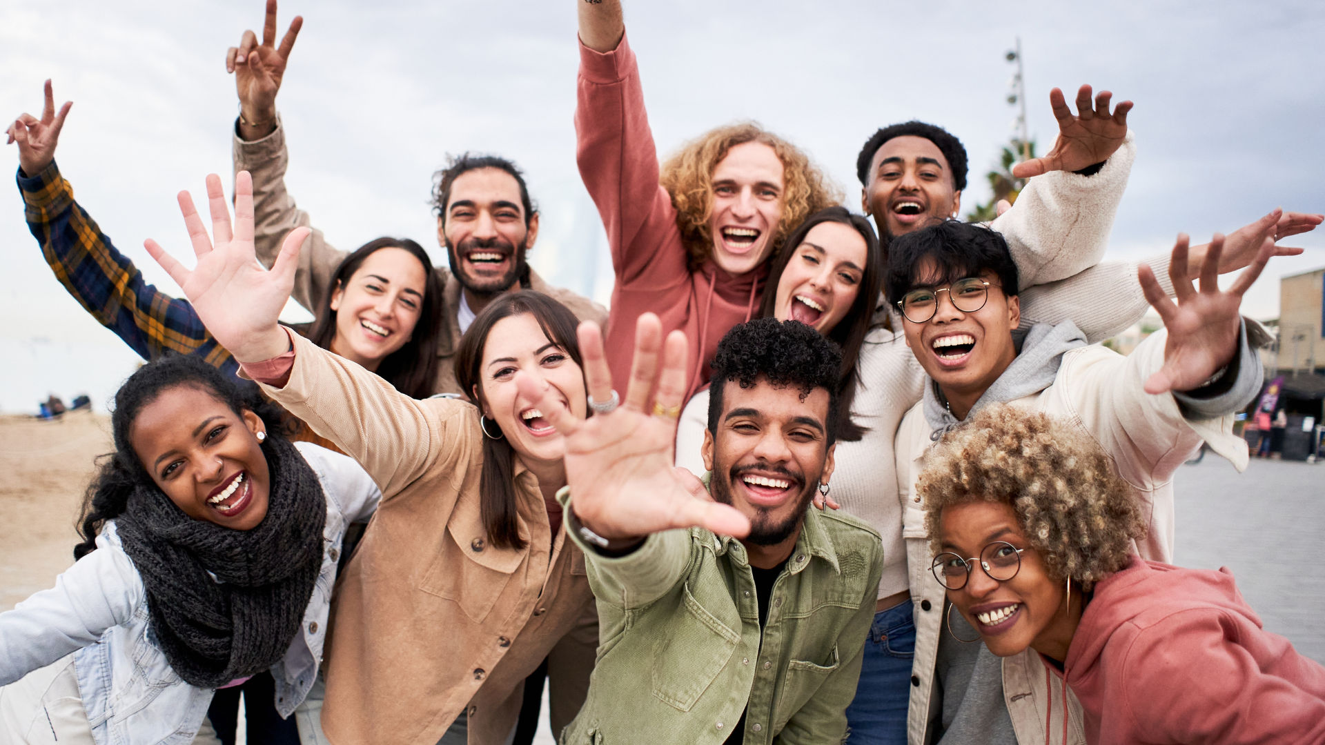 A diverse group of people smiling and waving at the camera