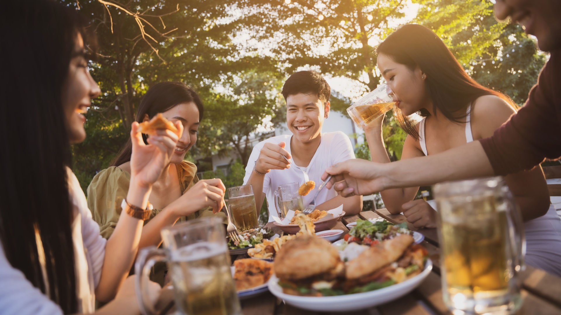A group of friends enjoying a meal together at a restaurant, smiling and sharing food.
