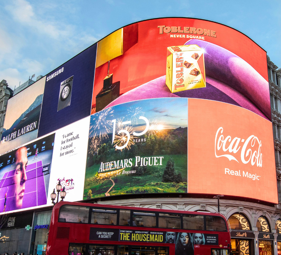 A large digital advertisement display on a building, featuring various brands
