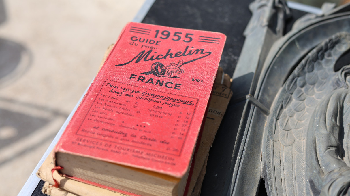A vintage 1955 Michelin guidebook for France, resting on a surface next to a tire