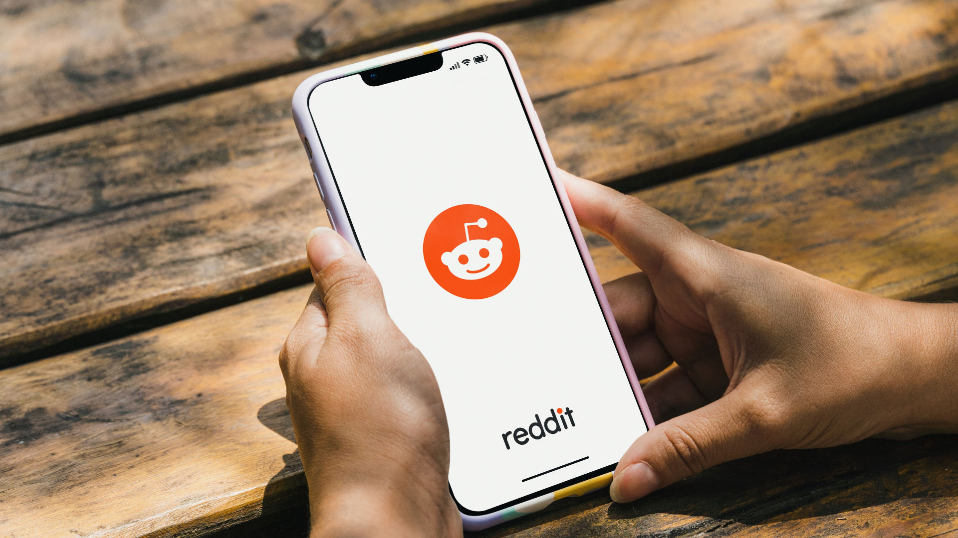 Person holding a phone with Reddit icon on screen