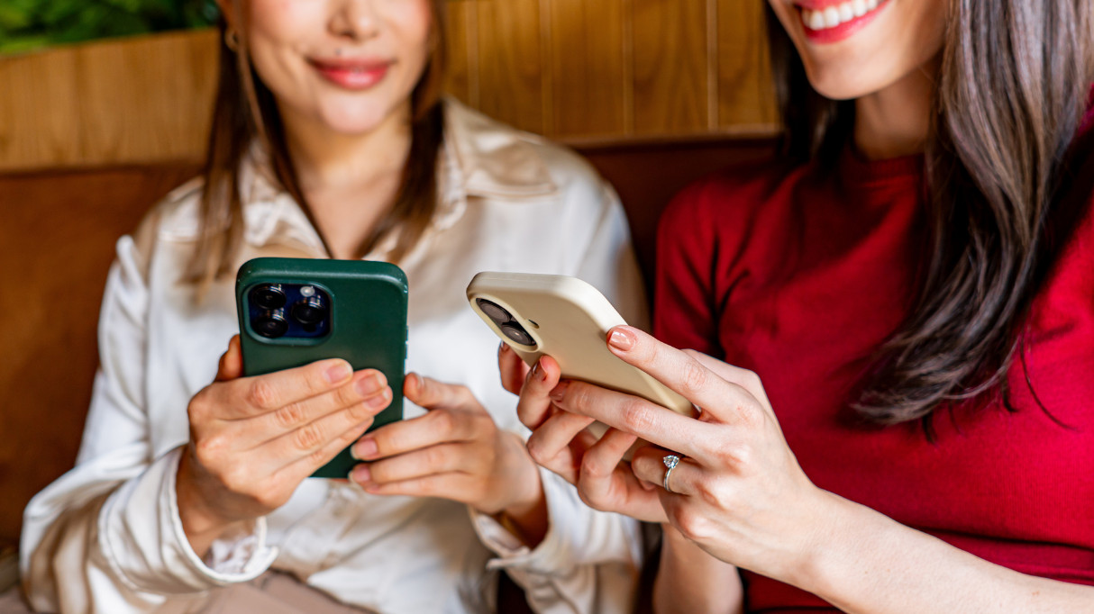 Two women smiling and holding phones