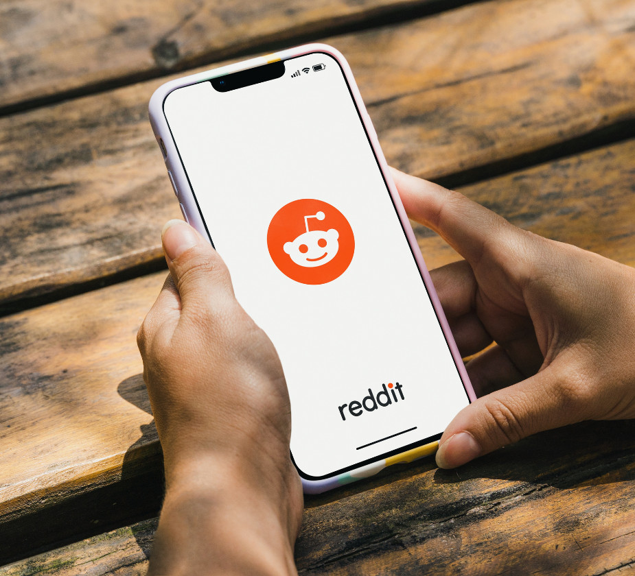 Person holding a phone with Reddit icon on screen