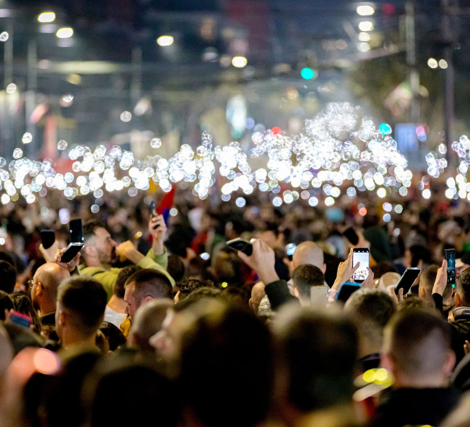 Crowd holding up phones with lights on in a nighttime setting.