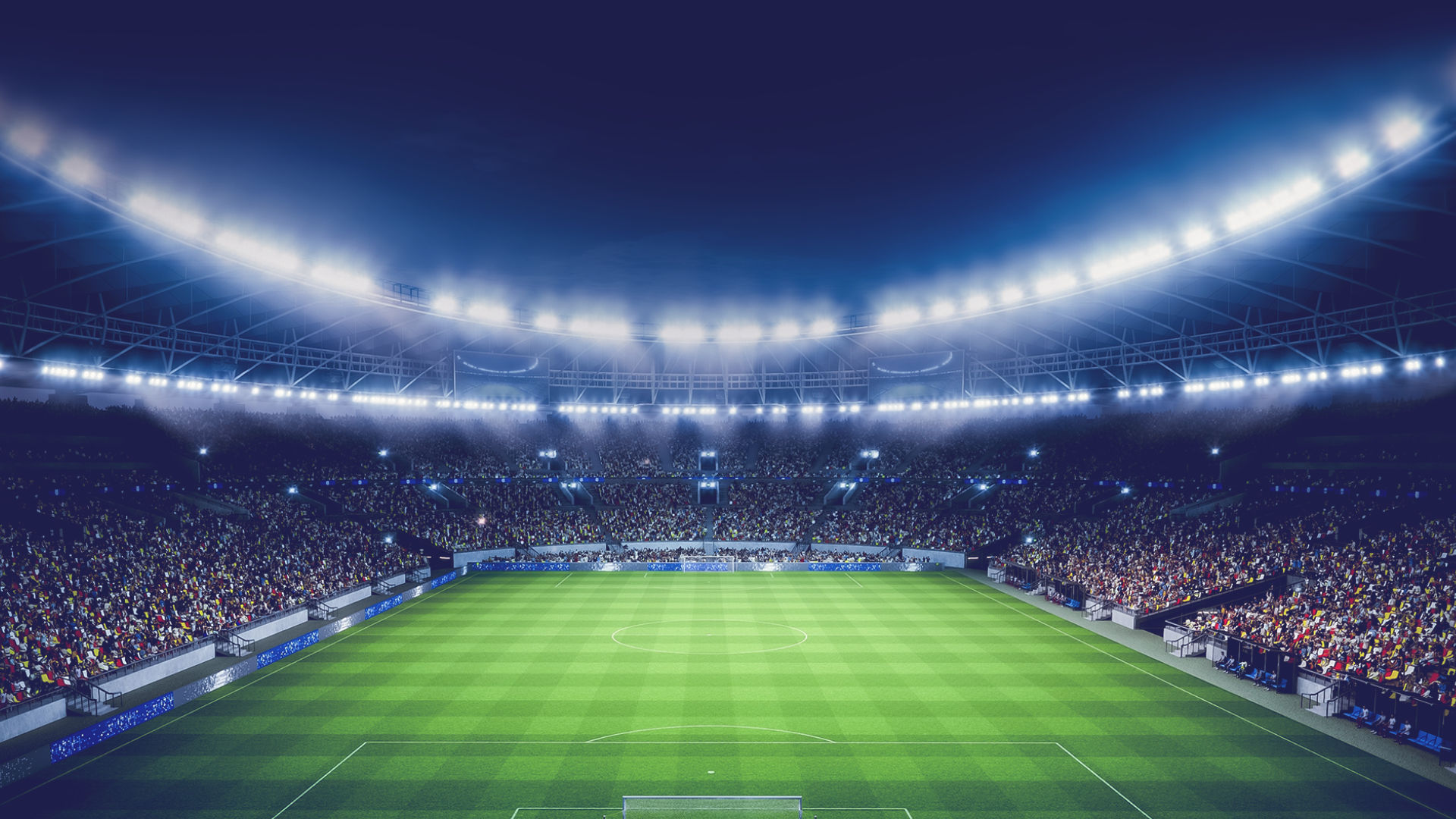 A brightly lit soccer stadium filled with a cheering crowd. The atmosphere is vibrant and exciting, under a clear night sky.