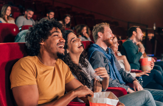 A couple at the cinema laughing whilst watching a movie