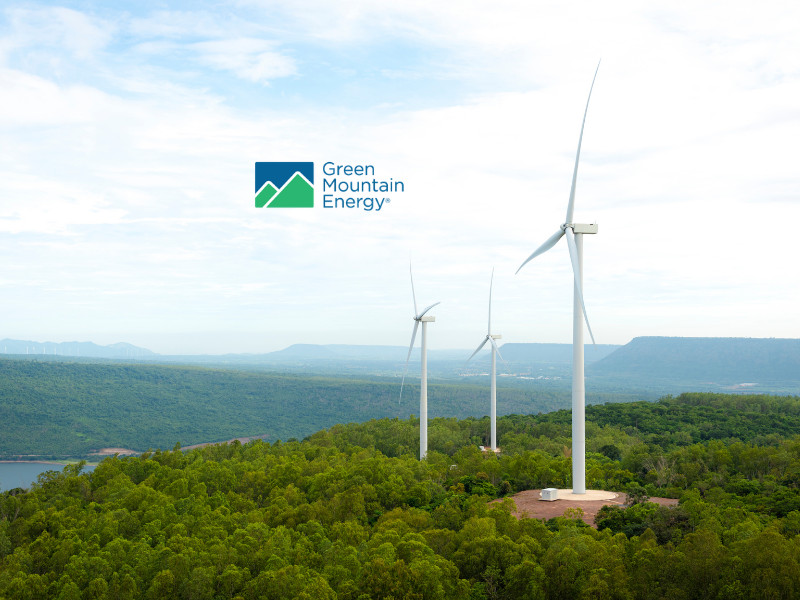 Green Mountain Energy Rewards Club graphic featuring wind turbines over a forest and lake landscape.