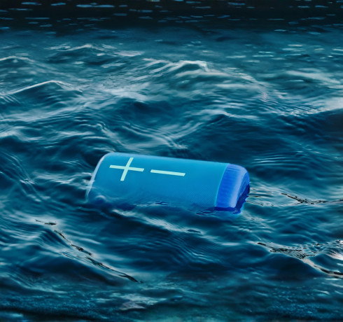 Blue Logitech portable speaker floating in ocean water with the message “Get More. Boom.” and Ultimate Ears branding.