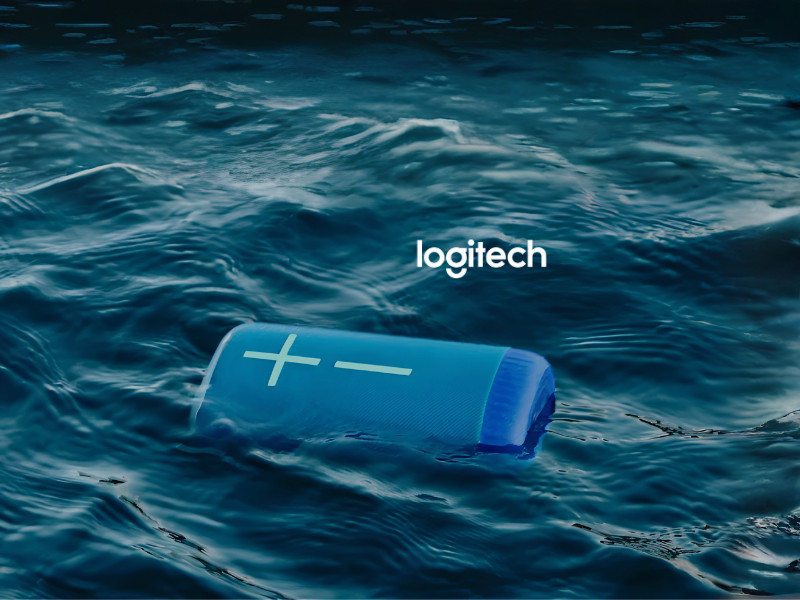 Logitech Ultimate Ears promotional graphic featuring a blue portable speaker floating in ocean water with “Get More. Boom.” text.