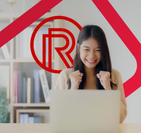 A young woman is smiling and celebrating in front of a laptop.