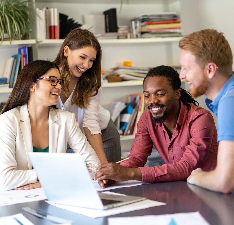 Four people looking at a laptop and laughing
