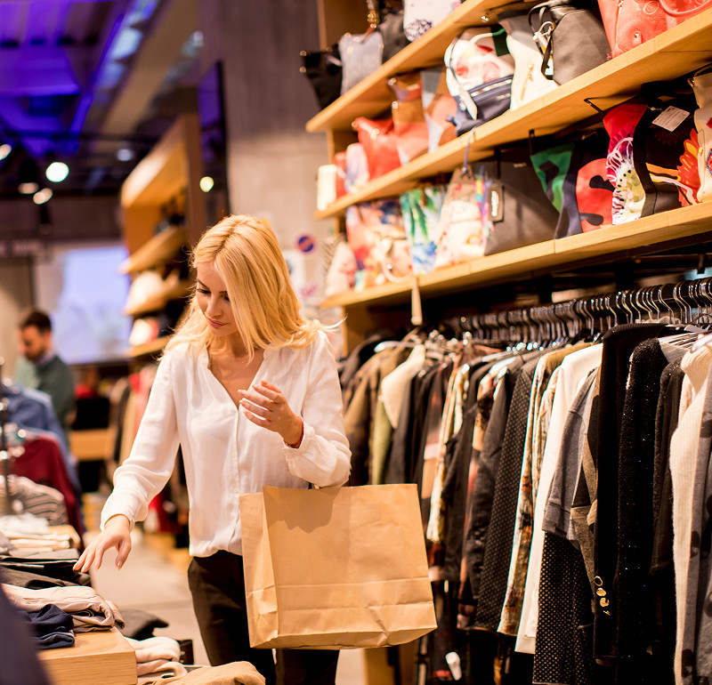A woman with a shopping bag shopping for clothes