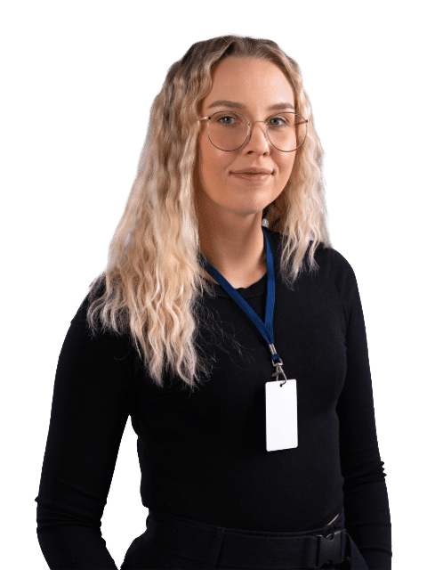 Eine kompetente IT-Systemadministratorin mit Brille und ID-Badge steht vor neutralem Hintergrund.