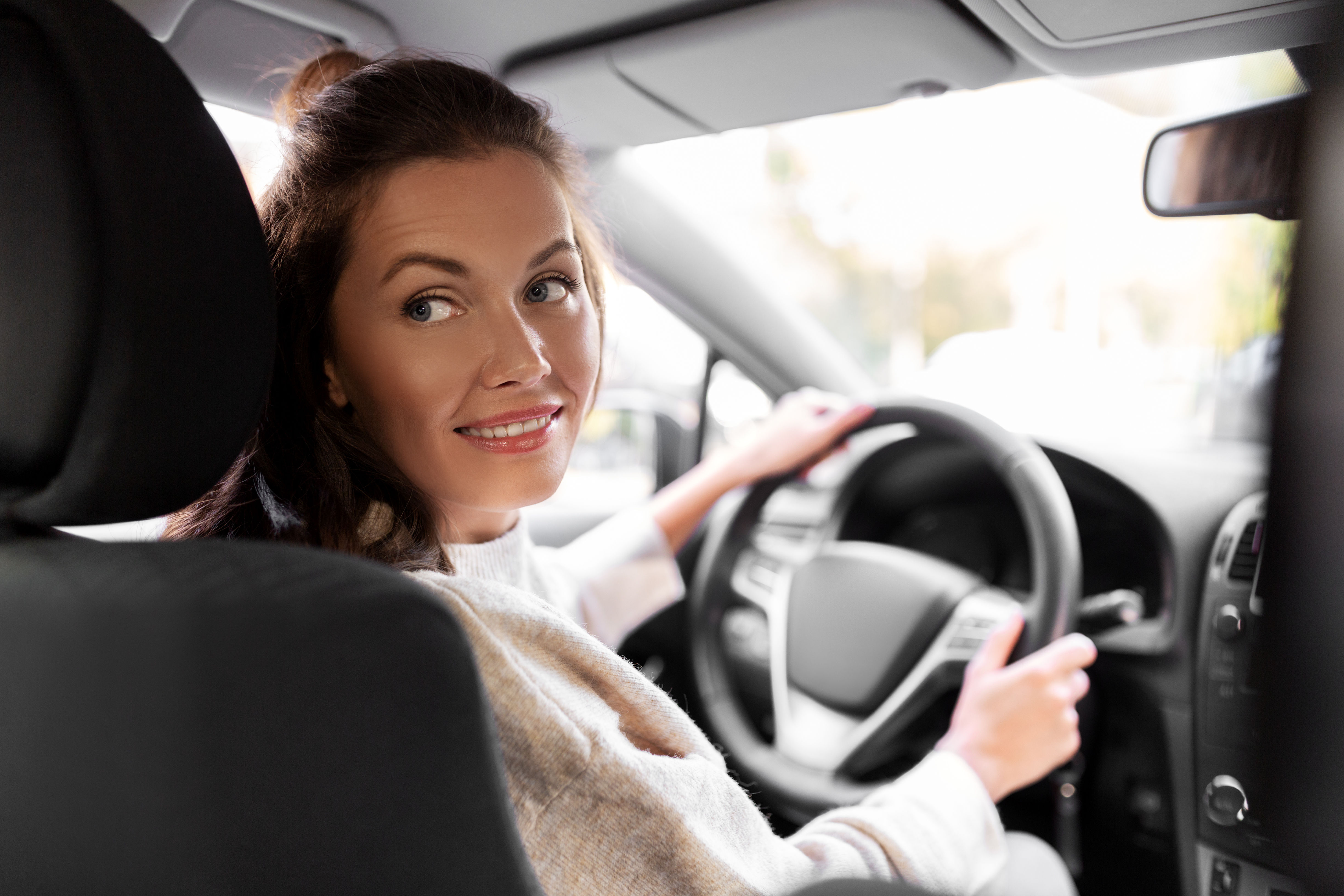 Pourquoi choisir un comparateur de location de voiture Femme souriante au volant de sa voiture de location