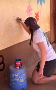 School pupil painting a mural at a school in Kenya.