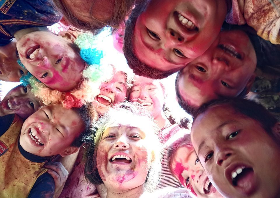 group of children and a gap year volunteer celebrating Holi in India
