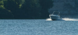 white boat rides alongthe river, past the fisherman on the boat