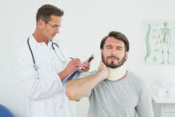 Male doctor examining a patient's sprained neck in the medical office