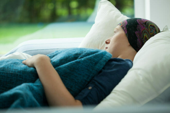 Young sick woman with cancer lying in hospital bed