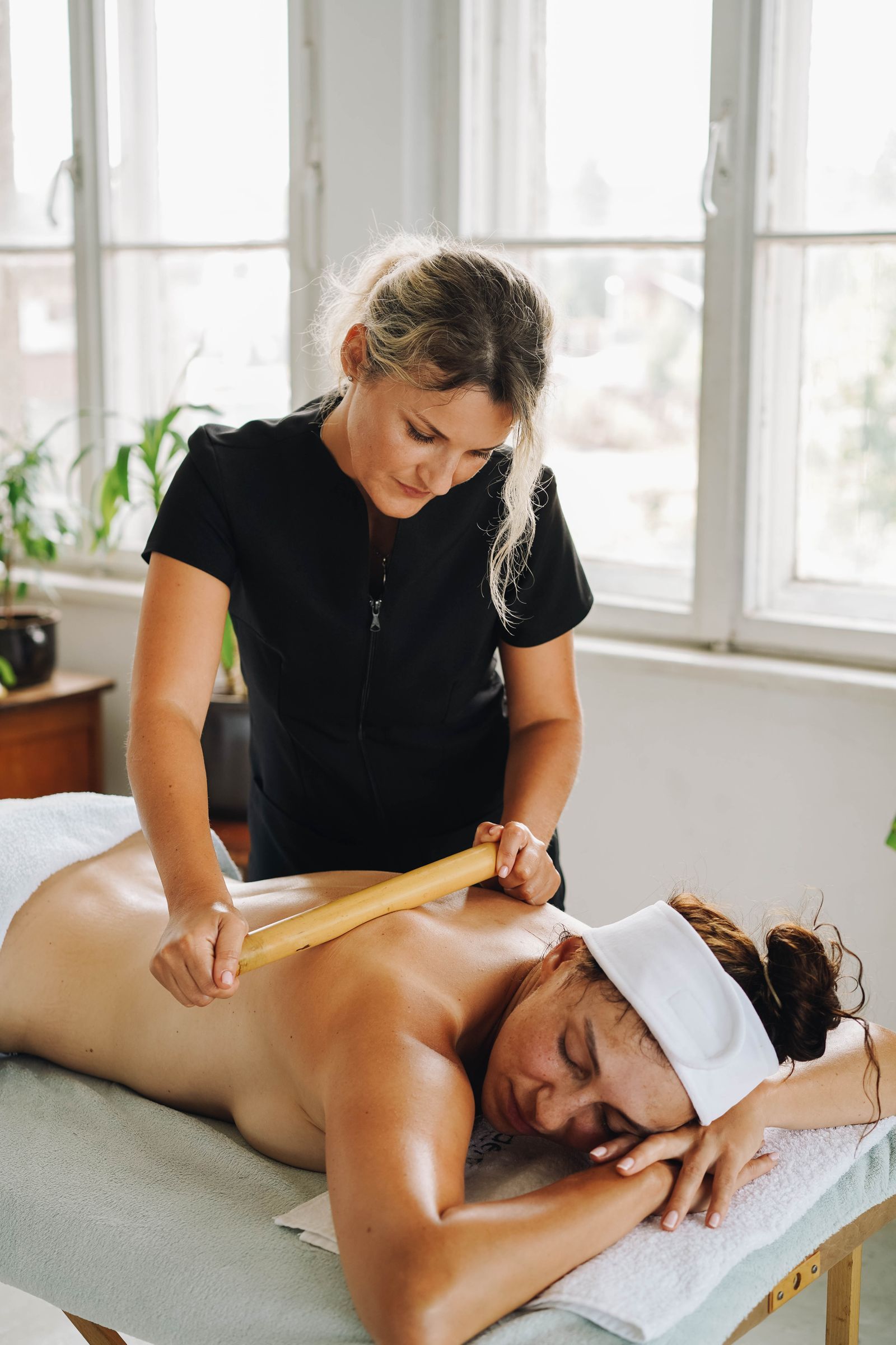 A wooden body tool worked over a client’s back in a bright treatment room