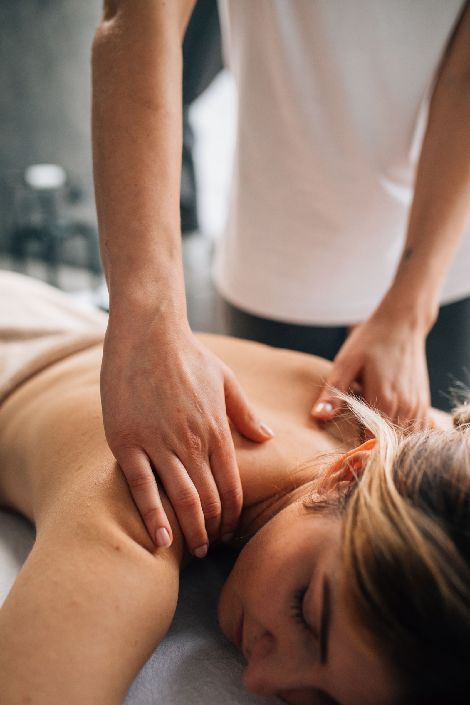 A therapist’s hands working a client’s shoulders during a massage
