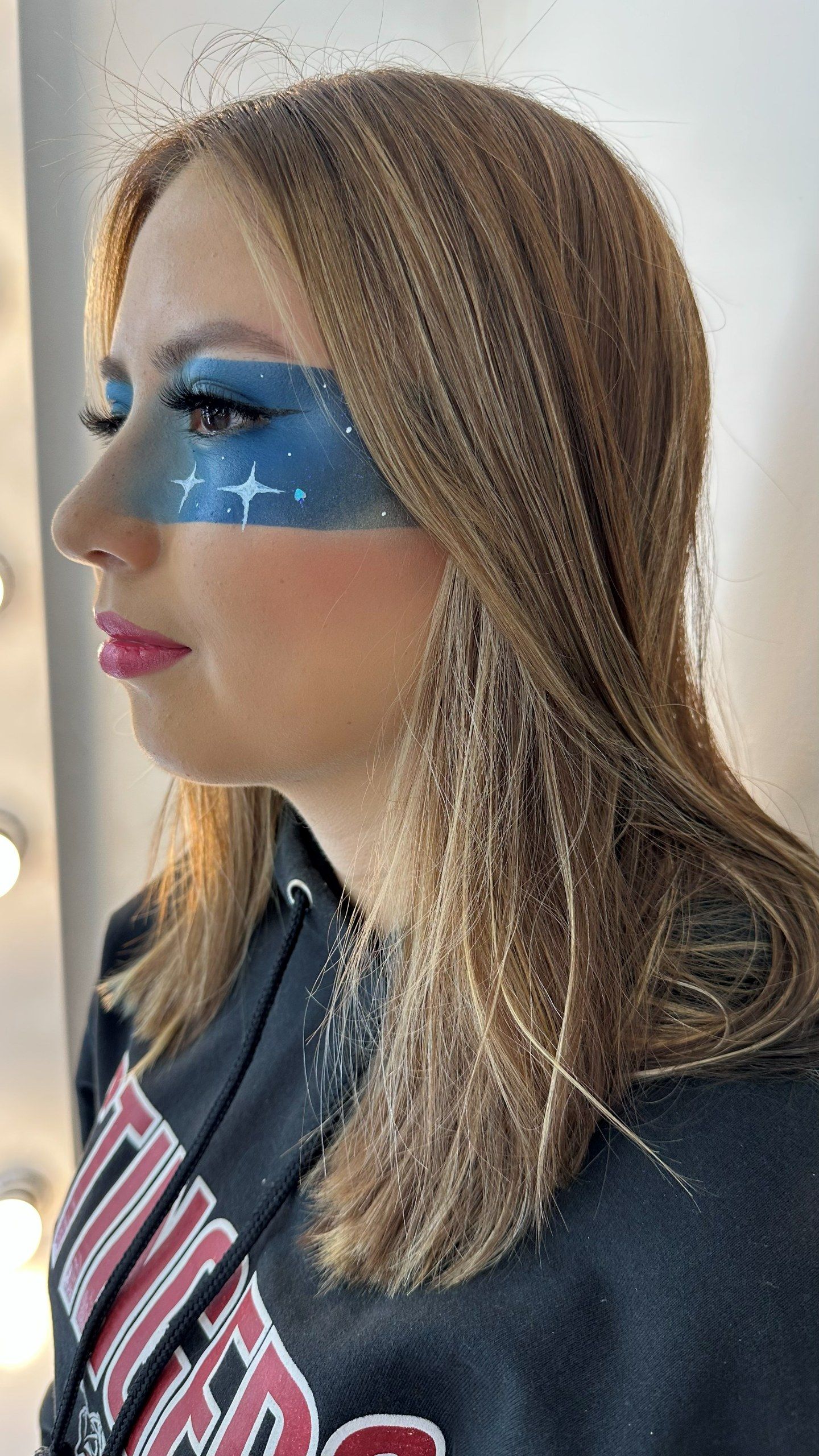 El mismo maquillaje gráfico azul con estrellas blancas, con la cabeza girada