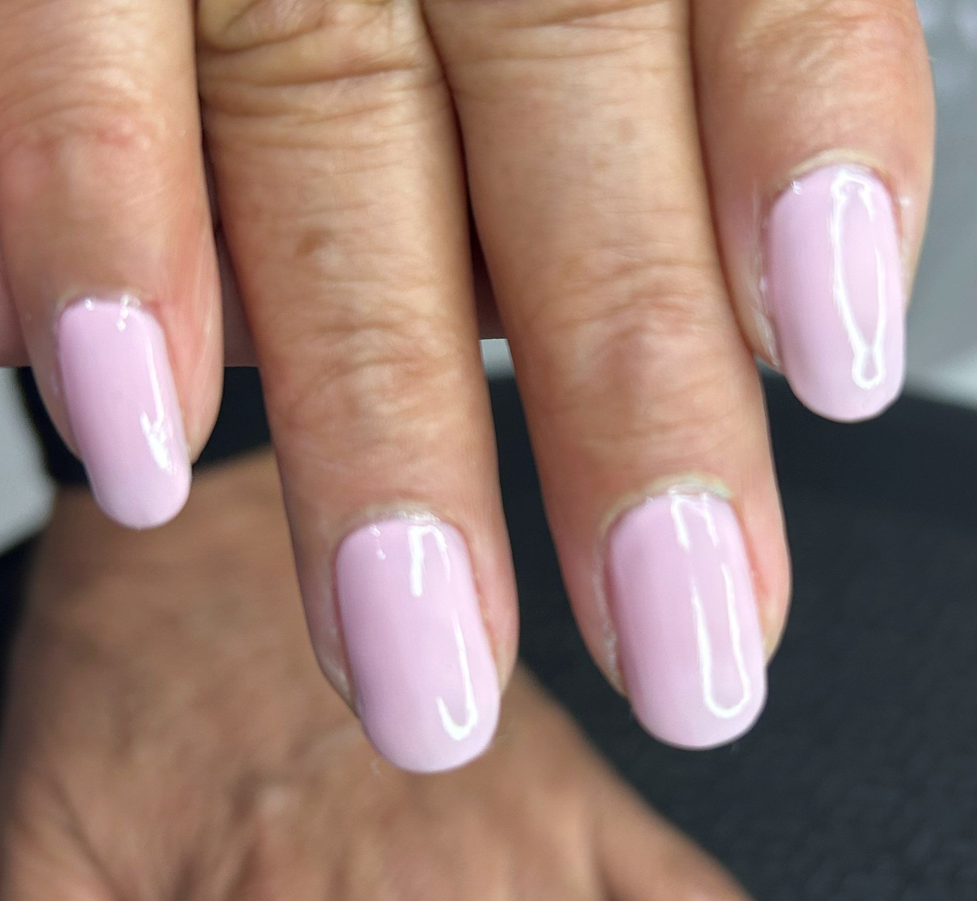 Uñas en rosa pálido brillante sobre dedos superpuestos