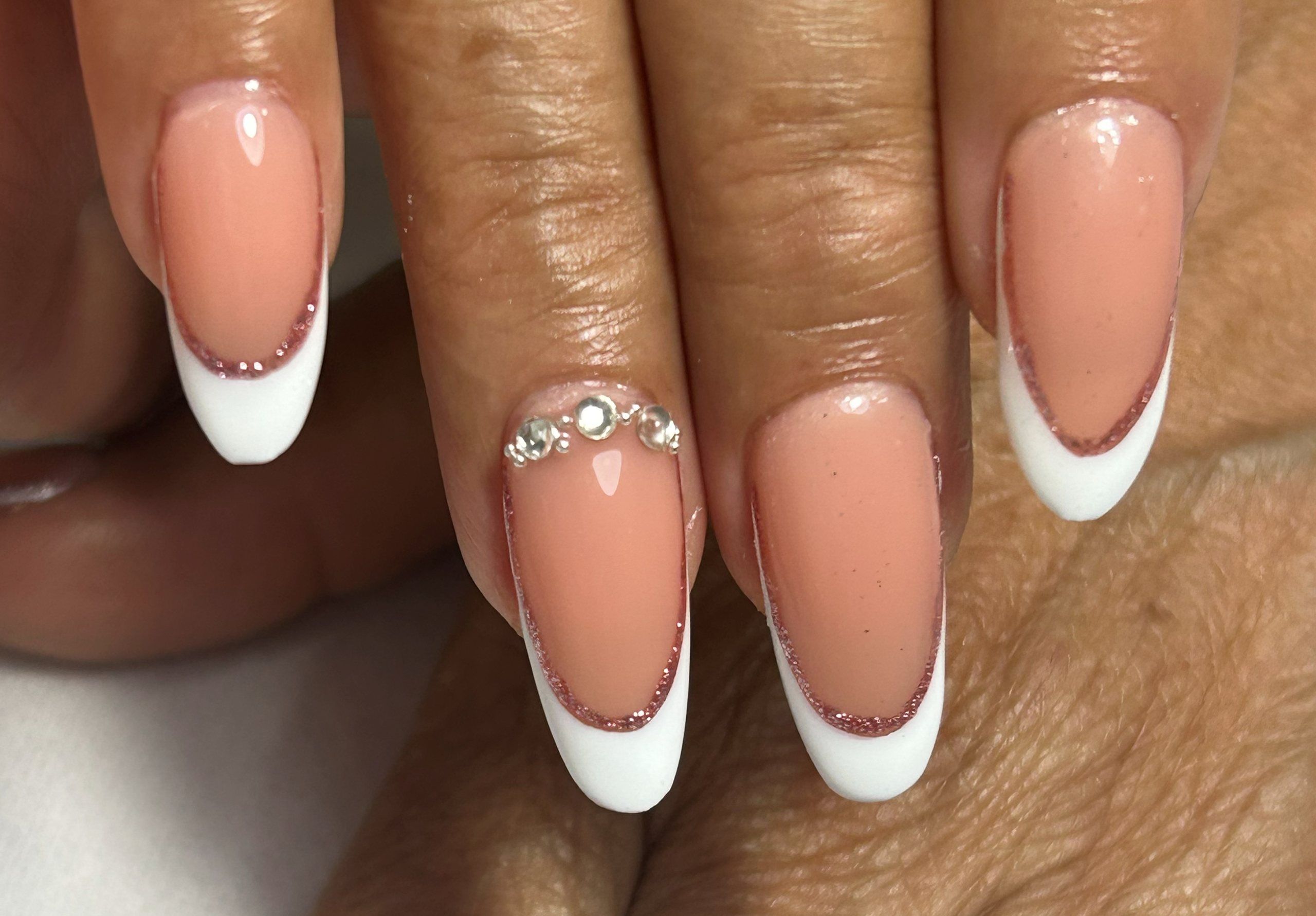 Uñas durazno con francesa blanca y cristales pequeños sobre la línea de la sonrisa