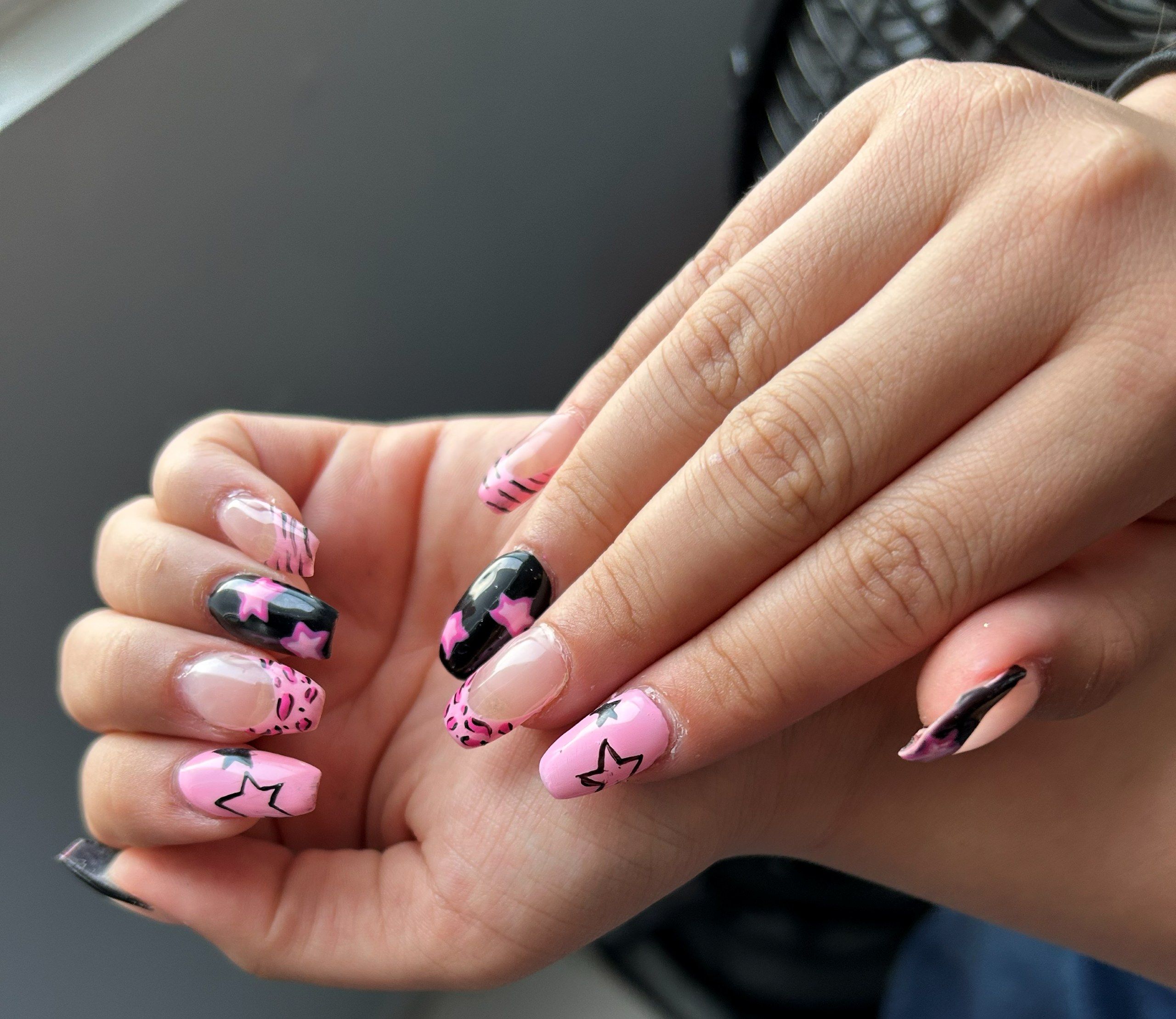 Uñas rosa y negro con estrellas pintadas a mano, una uña con manchas de leopardo y líneas finas de francesa